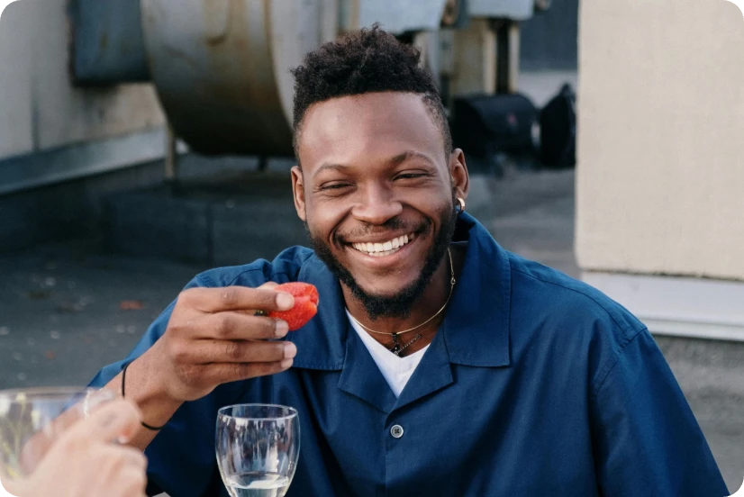a smiling man holding a strawberry