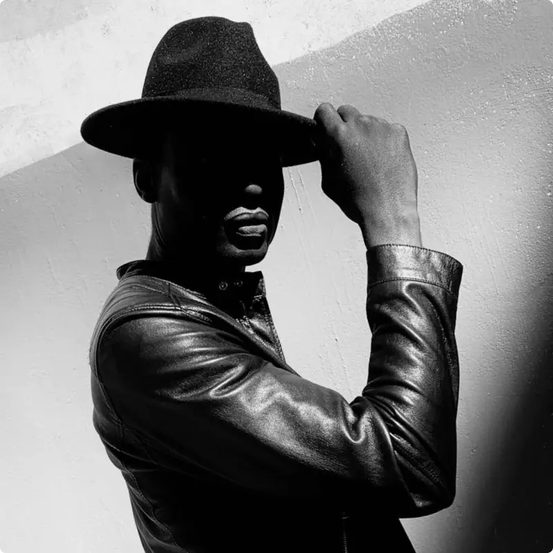 a black man touching brim of his hat