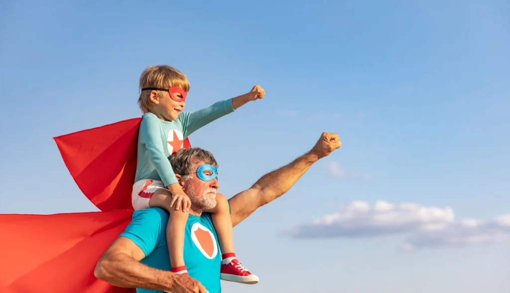 A father and son are portraying the Superman look with the dad carrying his son on his back