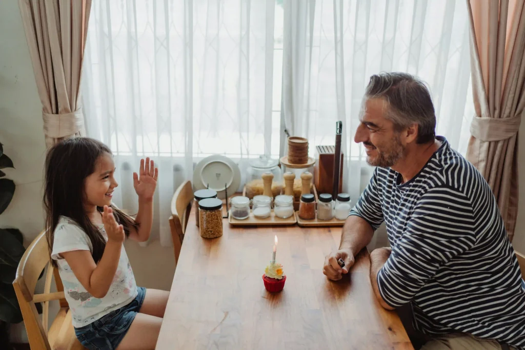 a daughter and a dad sitting beside the desk talking and smiling