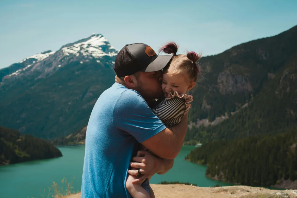 a father is holding and kissing a cute daughter